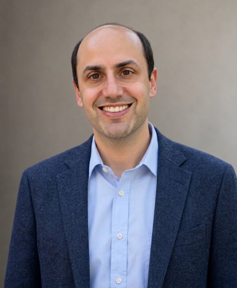 Matt Freeman, founder of Luminary Counsel, smiling in a navy jacket and light blue shirt against a warm gray wall.